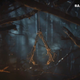 The Assassin's Creed logo is made out of twigs and hangs from a tree.